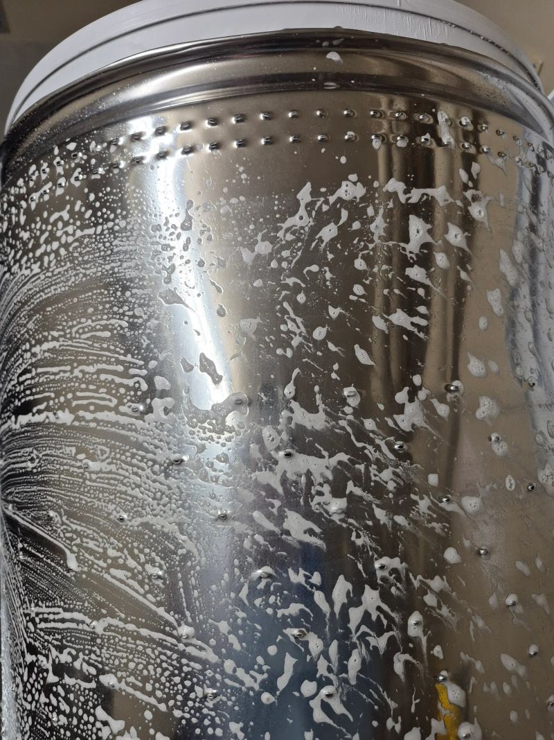 Stainless steel surface with soap suds and water droplets.