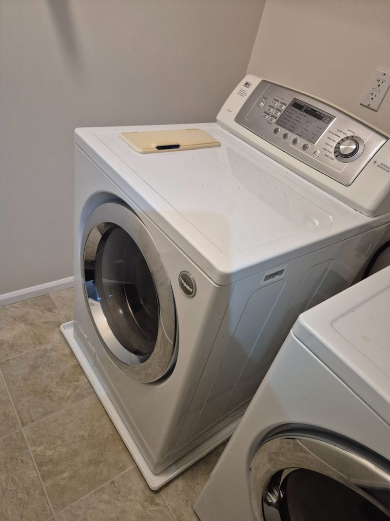 A modern washing machine in a laundry room setting, showcasing A&H Appliance Repair service.